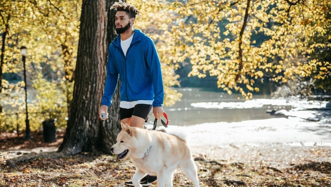 man and a large dog walking along a river near the carson apartments in 30075